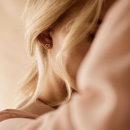 A model wearing the 8mm Brilliance Heart Hollow Earrings in golden titanium