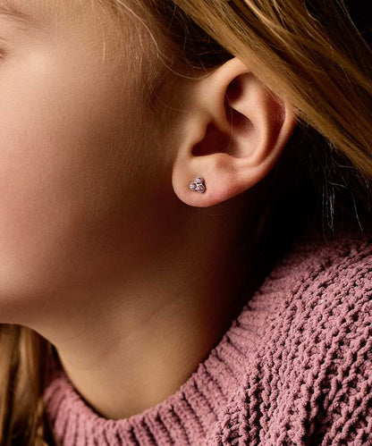 Close up of a person wearing the nickel-free Golden Titanium 6mm clover earrings with light rose colored Swarovski crystal stones.