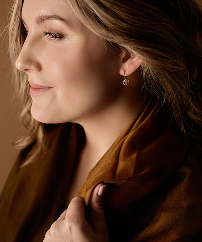 Woman wearing the hypoallergenic golden titanium 14mm pendants with a round bronze colored Swarovski crystal stone