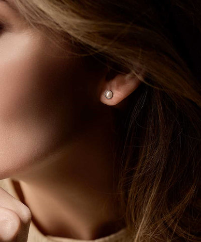 Close-up of a person wearing a nickel-free silver titanium 6mm pearl earring with a blurred background