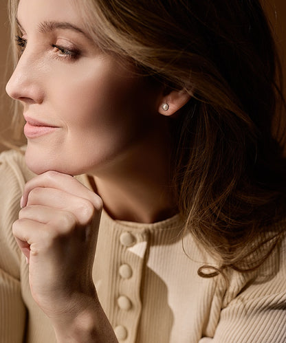 Close-up of a woman wearing a 6mm pearl earring with a soft focus background