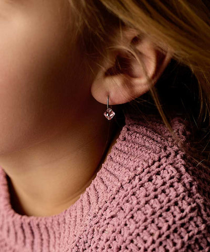 Close-up of a person wearing a pink earring with a blurred background
