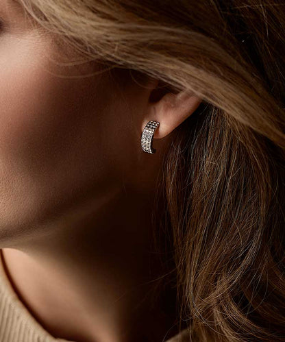 Close-up of a person wearing a crystal pendant earring with small stones.